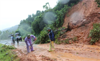 Workers clear a road affected by landslides to avoid traffic congestion